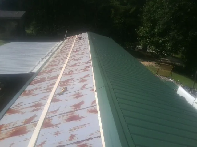 Old rusted panels beside newly installed green metal roofing — Wind Damage Roof Repair by Roofing Brothers in Boyds