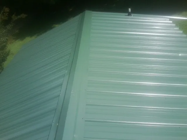 New green metal panels meeting at the ridge of a roof — Flat Roof Repair work by our crew in Boyds