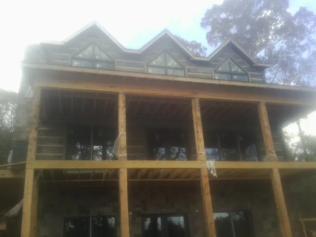 Dormers and porch framing on a large log home under construction — Roof Coating work by our crew in Boyds