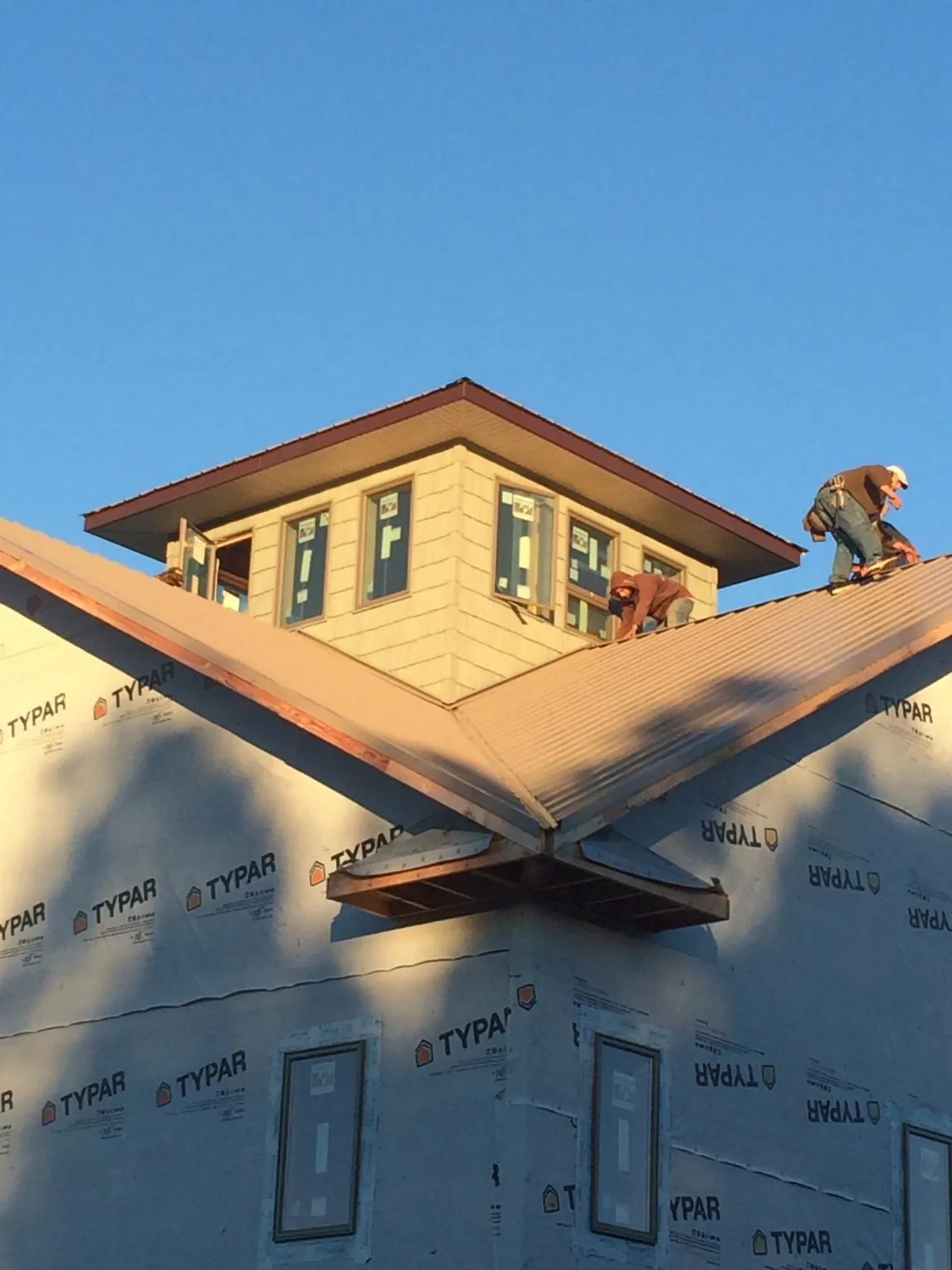 Roofers working around a rooftop cupola on a new metal roof at sunset — Roof Waterproofing in Boyds by Roofing Brothers